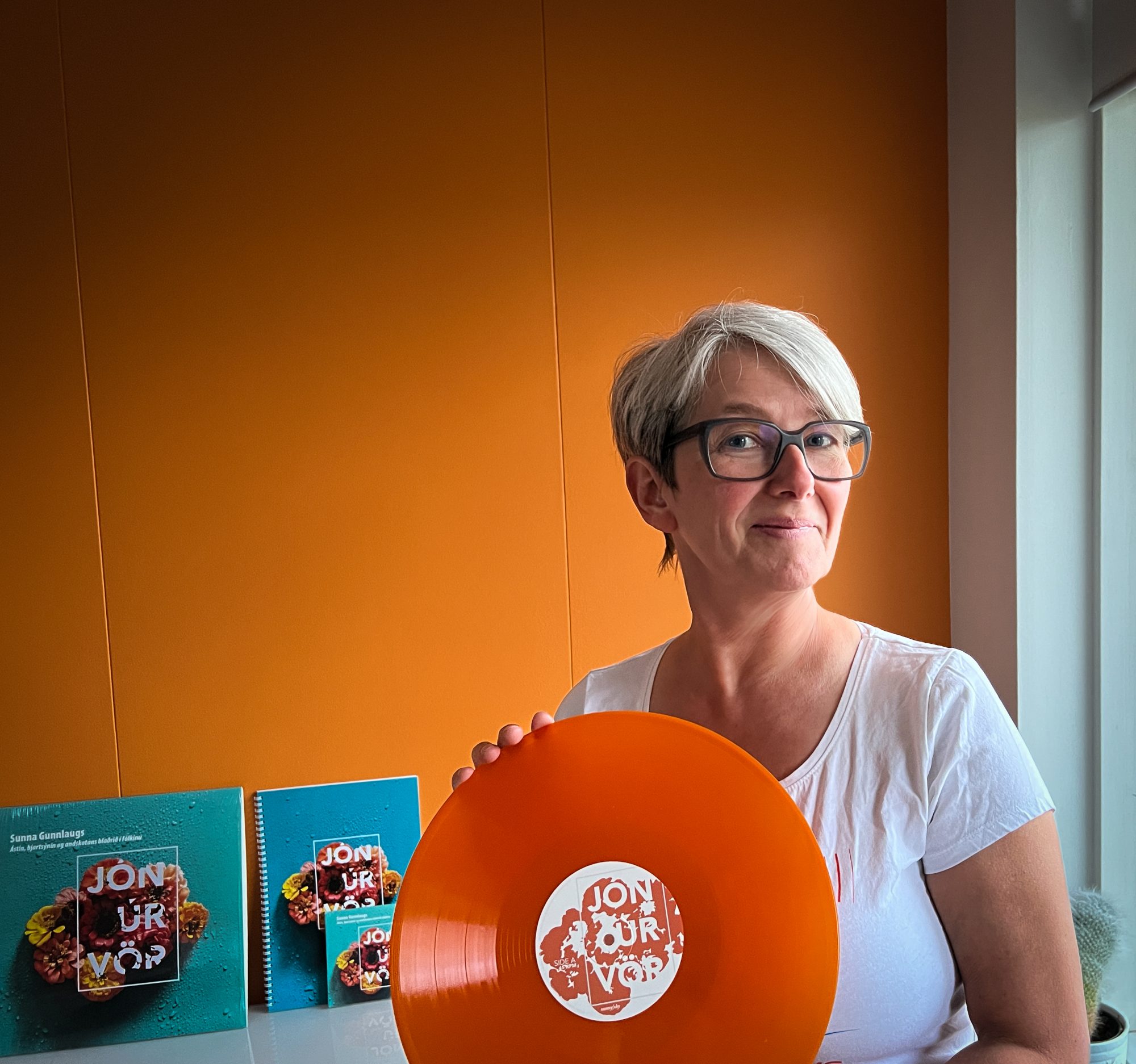 Sunna Gunnlaugs holding a copy of her new orange vinyl LP of music to Icelandic poetry.